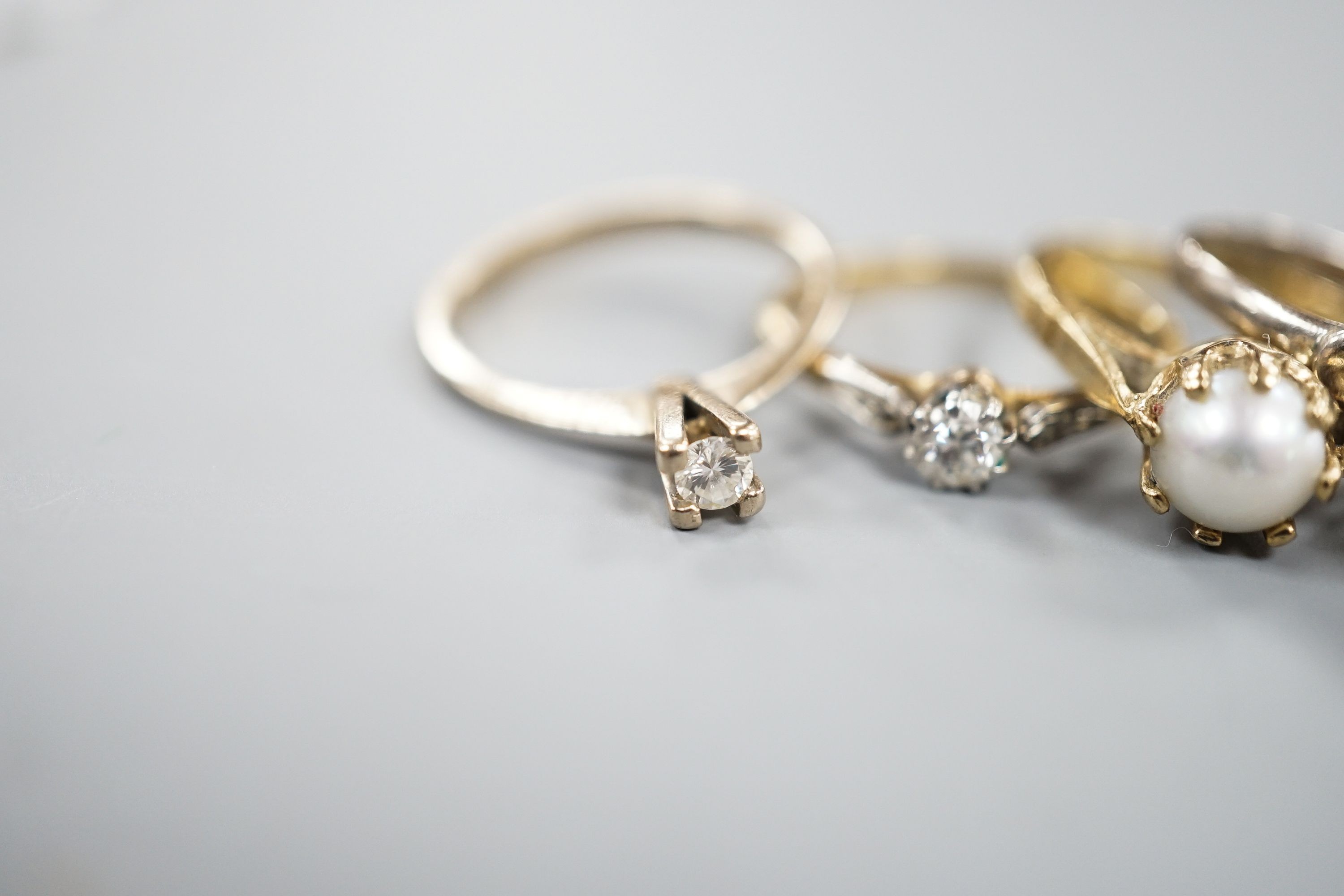 A 750 white metal and solitaire diamond ring, size K, gross 2 grams, two other yellow or white metal diamond set rings, gross 3.4 grams and two 9ct and gem set rings including cultured pearl, gross 6.3 grams.
